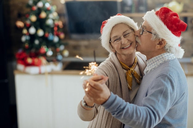 Amorosa pareja senior bailando el día de Navidad en casa