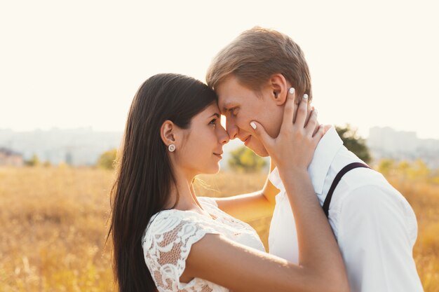 Amorosa pareja vestida de blanco besándose al aire libre