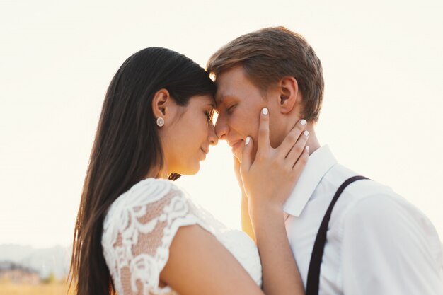 Amorosa pareja vestida de blanco, lista para besarse al aire libre con clos