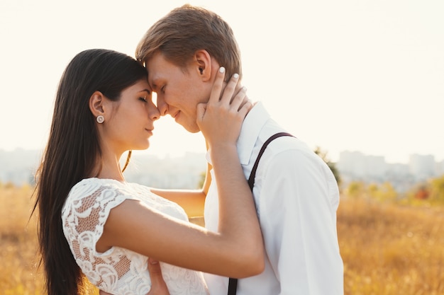 Amorosa pareja vestida de blanco, lista para besarse al aire libre