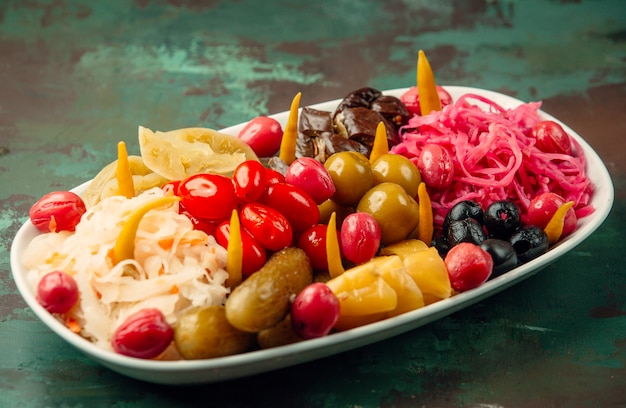 Amplia selección de frutas y verduras marinadas en un plato blanco.