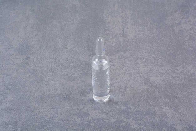 Foto gratuita ampolla médica transparente sobre mesa de mármol.