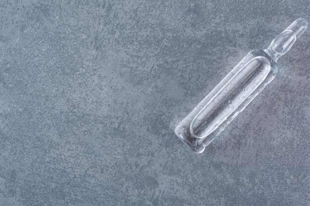 Ampolla médica transparente sobre superficie de mármol