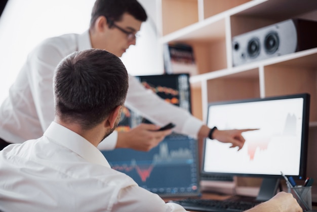 Analizando datos. Primer plano del equipo de negocios jóvenes que trabajan juntos en la oficina creativa, mientras que la joven apuntando a los datos presentados en el gráfico con lápiz