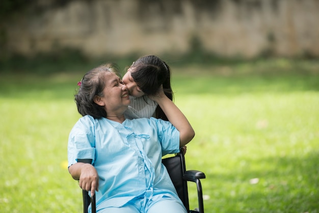 Anciana abuela en silla de ruedas con nieta en el jardín del hospital