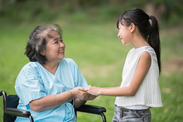 Anciana abuela en silla de ruedas con nieta en el jardín del hospital