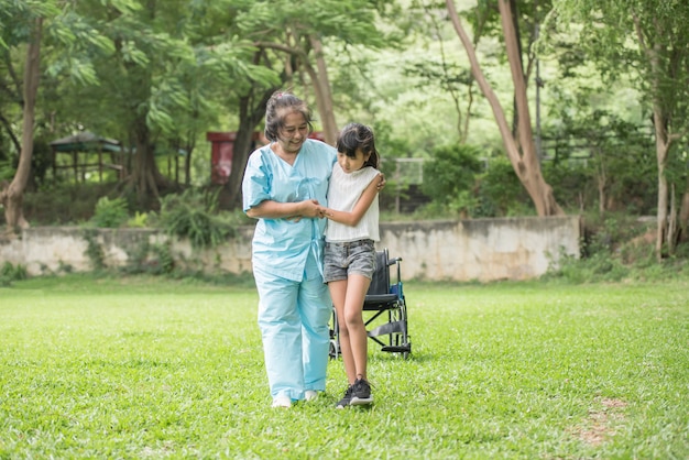 Anciana abuela en silla de ruedas con nieta en el jardín del hospital