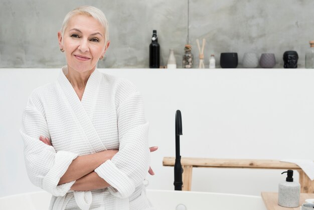 Anciana en bata de baño posando con los brazos cruzados