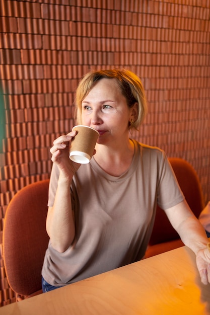 Foto gratuita anciana bebiendo café en una cafetería