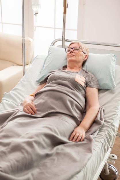 Anciana cansada acostada en la cama en un hogar de ancianos. mujer jubilada.