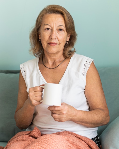 Anciana en casa durante la pandemia disfrutando de una taza de café