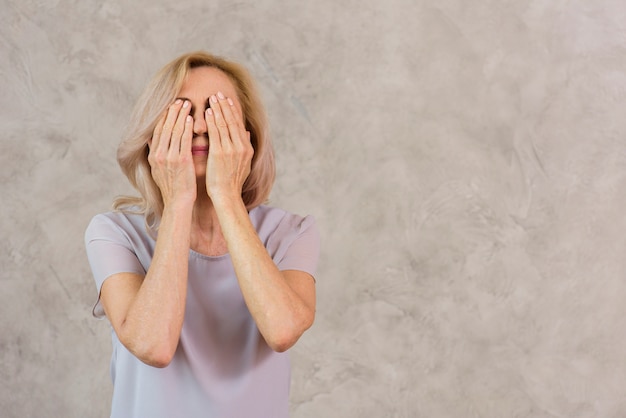 Anciana cubriéndose la cara con espacio de copia