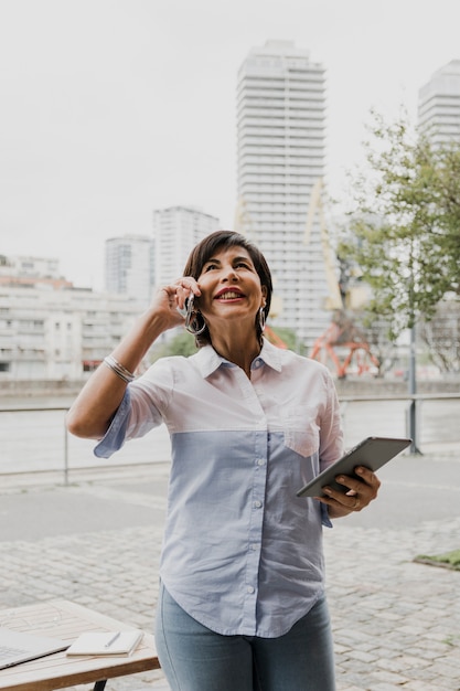 Foto gratuita anciana hablando por teléfono sobre fondo urbano