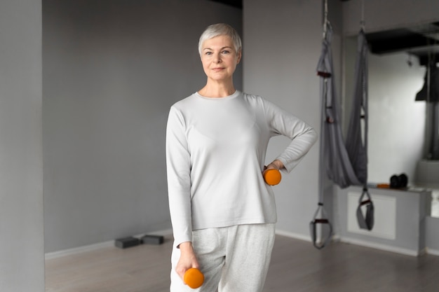 Anciana haciendo ejercicios de pesas en el gimnasio