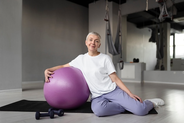 Anciana haciendo un entrenamiento de pelota de gimnasia en el gimnasio