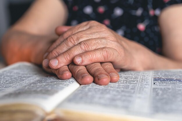 Una anciana lee las manos de la Biblia de cerca