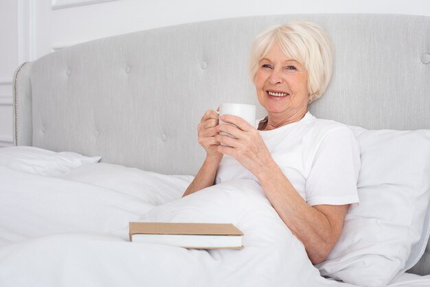 Anciana leyendo una taza en el dormitorio