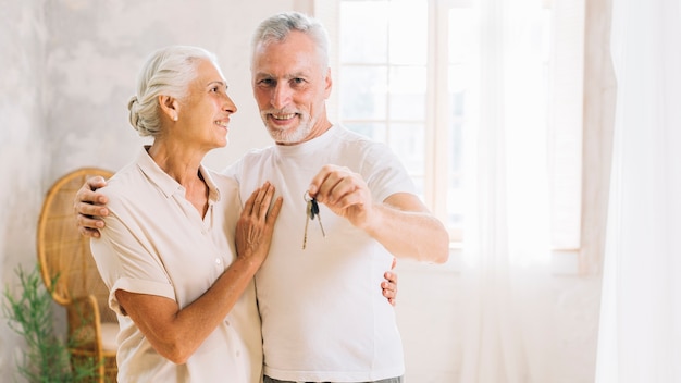 Una anciana mirando a su esposo mostrando la llave de la casa en casa