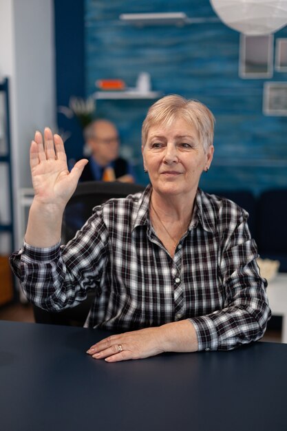 Anciana pensativa saludando a la gente en el curso de la conferencia en línea