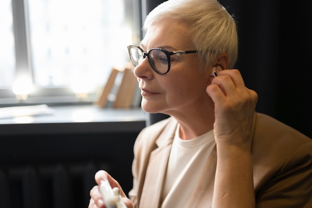 Anciana poniendo sus auriculares en sus oídos en un café