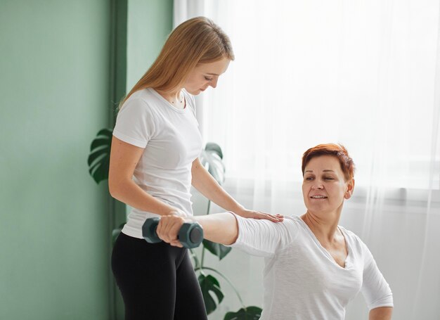 Anciana en recuperación covid haciendo ejercicios físicos con mancuernas