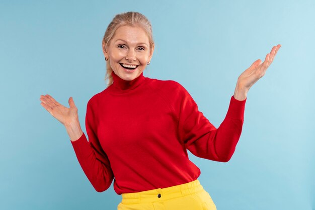 Una anciana rubia siendo feliz y sonriendo contra un fondo azul.