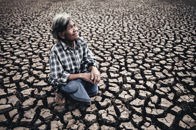 Foto gratuita una anciana está sentada mirando al cielo en clima seco, el calentamiento global