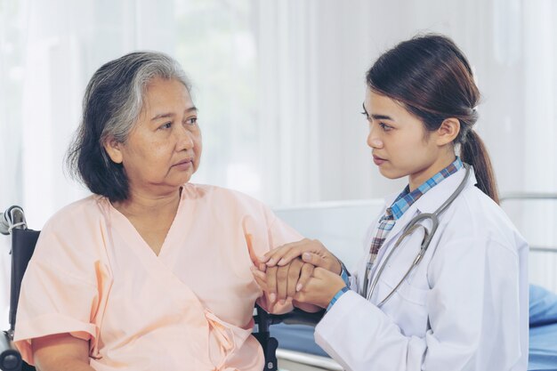 Anciana sonriendo con médico y visitando paciente mujer senior en sala de hospital