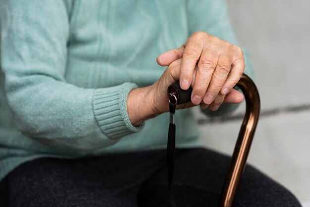 Anciana sosteniendo un bastón en sus manos