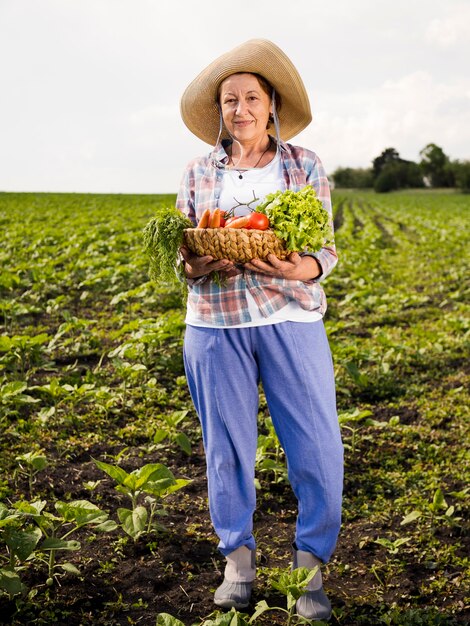 Anciana sosteniendo una canasta llena de verduras