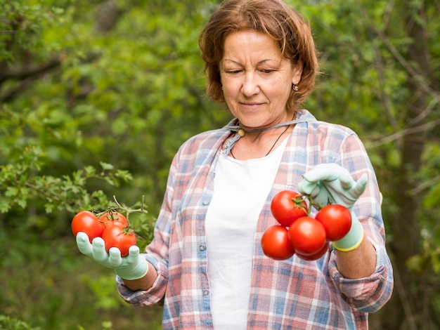 Anciana sosteniendo un montón de tomates