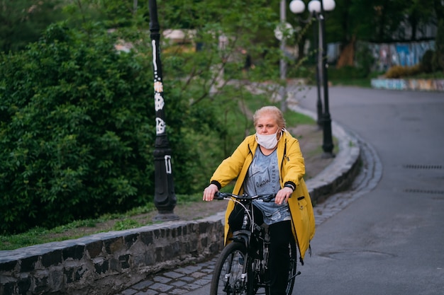 Anciana en su bicicleta con una máscara quirúrgica en la calle