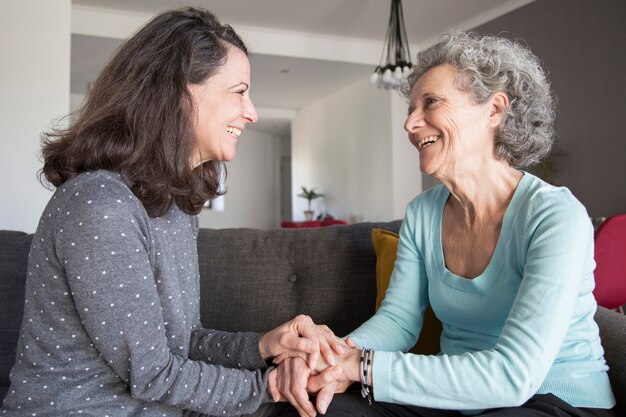 Anciana y su hija riéndose y tomados de las manos