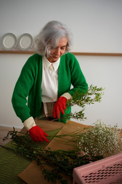 Una anciana de tamaño medio cuidando las plantas.