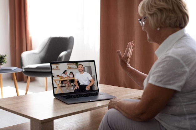 Foto gratuita anciana teniendo una videollamada con su familia