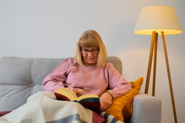 Foto gratuita anciana de tiro medio leyendo en casa