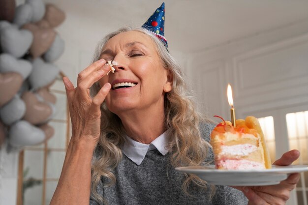Anciana de tiro medio sosteniendo pastel