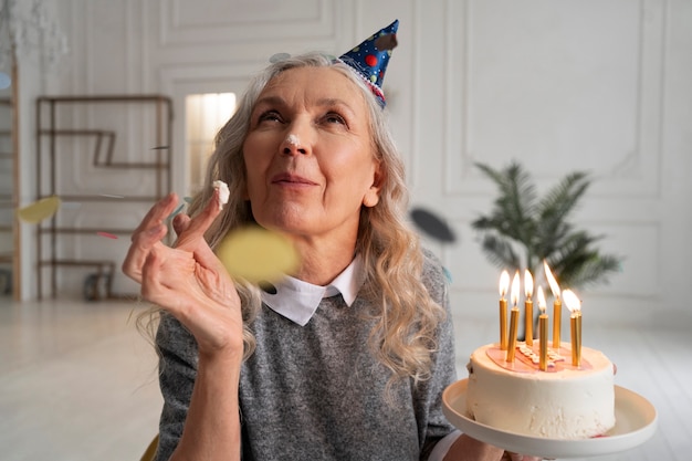 Anciana de tiro medio sosteniendo pastel