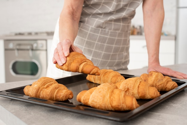 Foto gratuita anciana tomando un croissant de la bandeja