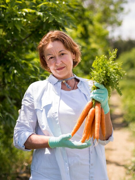 Anciana con zanahorias frescas en su mano
