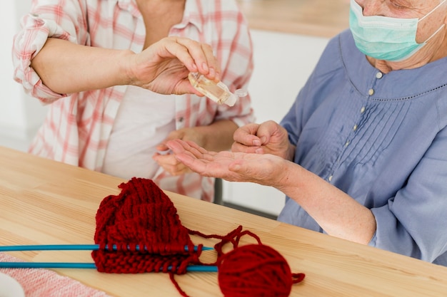 Foto gratuita ancianas en casa desinfectando sus manos