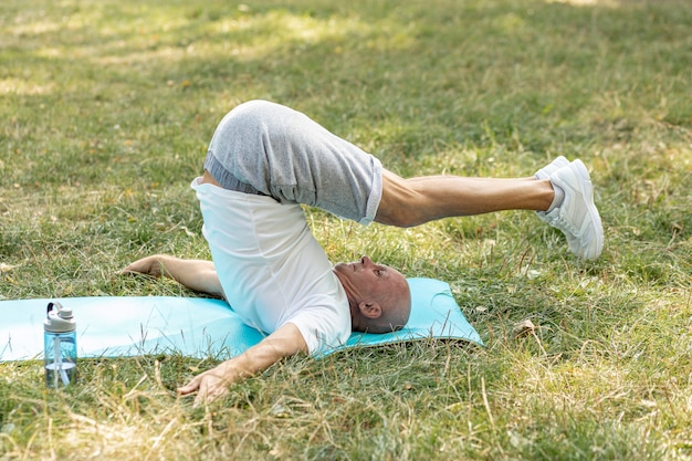 Anciano aguantando estiramientos en estera de yoga