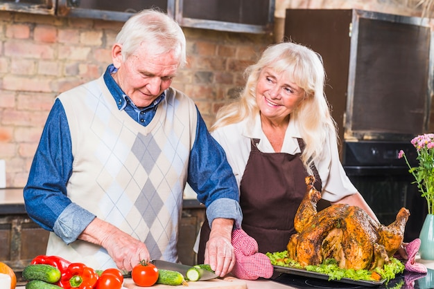 Anciano ayudando a su esposa a cocinar pavo