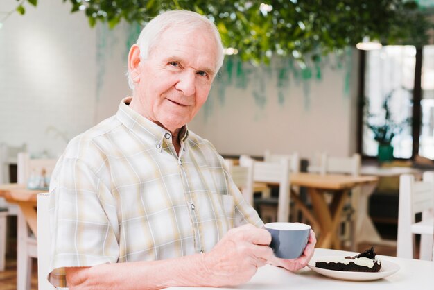 Anciano bebiendo té y mirando a cámara