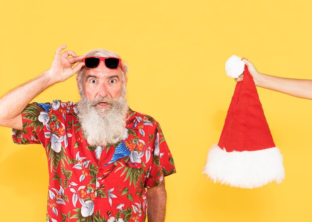 Anciano con camisa tropical y sombrero de navidad