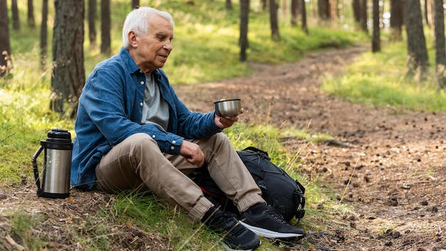 Anciano descansando mientras viaja en la naturaleza