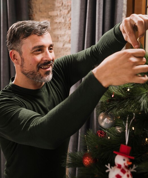 Anciano disfrutando de la decoración del árbol de navidad