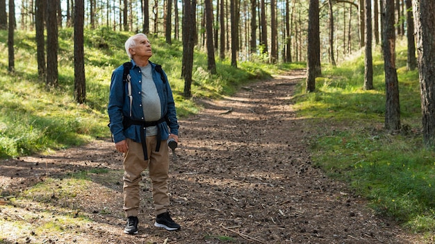 Anciano explorando la naturaleza mientras lleva mochila