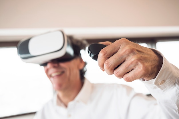 Un anciano con gafas de realidad virtual usando control remoto.
