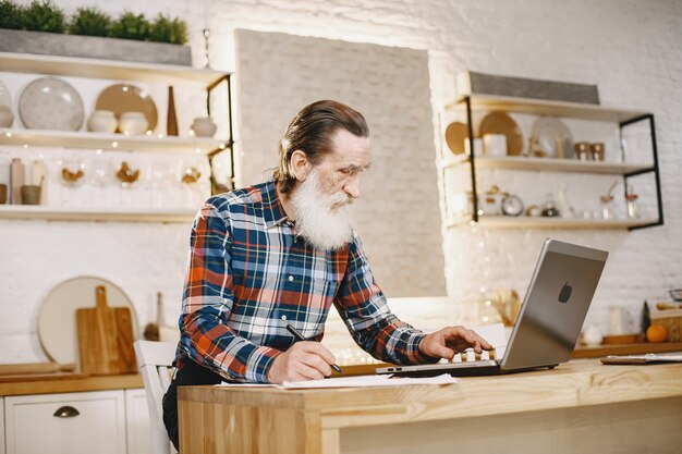 Anciano con laptop. Abuelo sentado en una decoración navideña.
